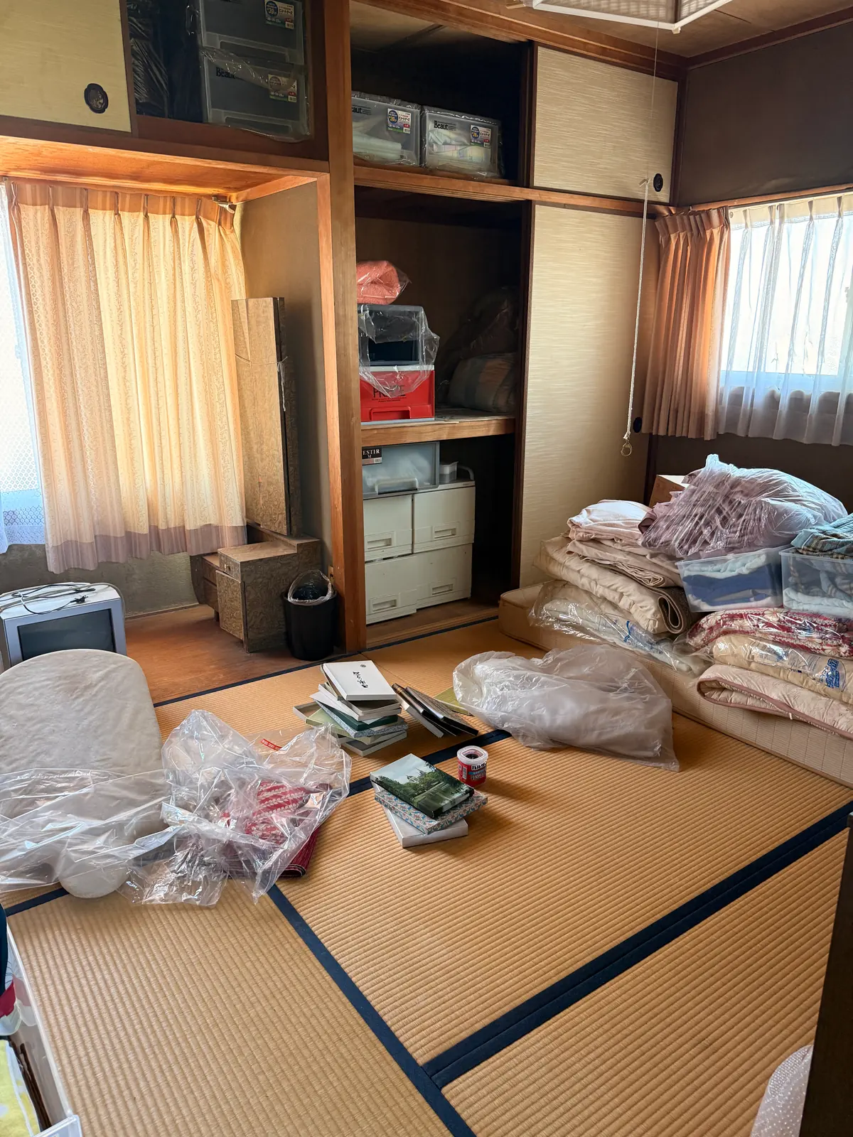 布団や収納ケースなどが残る実家の和室